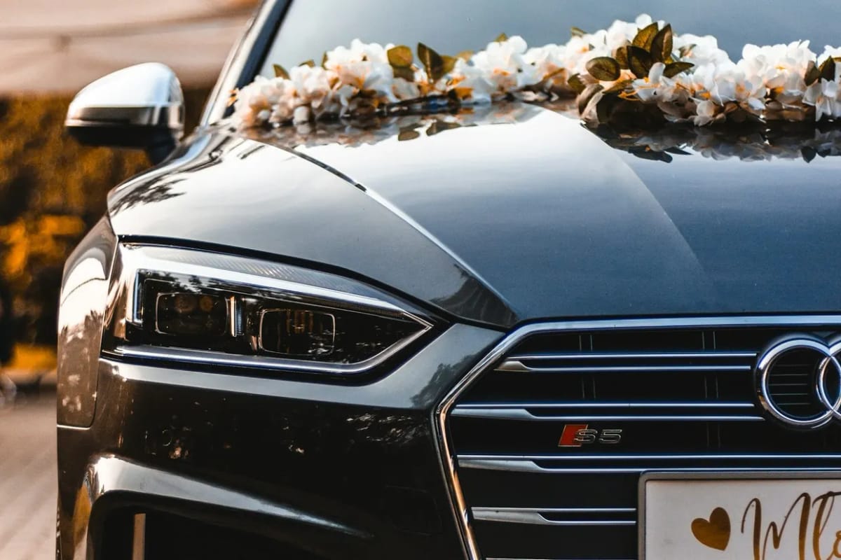 White flowers laid across the bonnet of a black wedding car