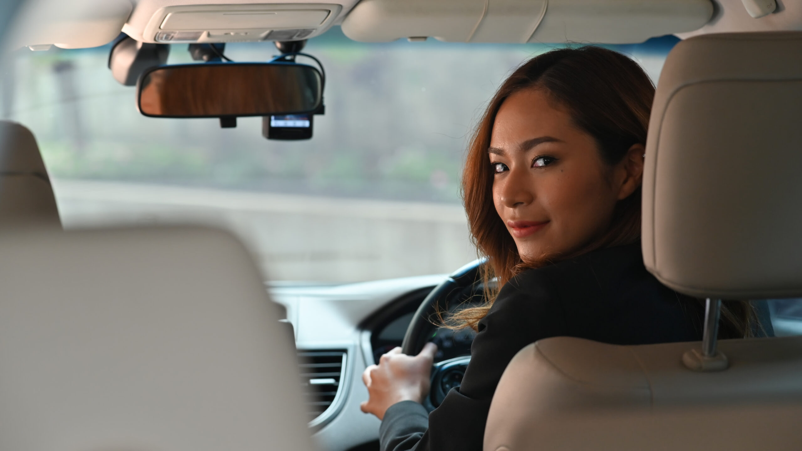 Photo of young beautiful business woman while driving a luxury c